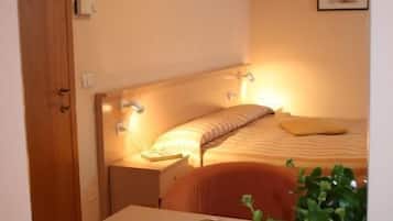 Ein Schlafzimmer mit einem Bett, einem Nachttisch, einer Lampe und einer Topfpflanze.