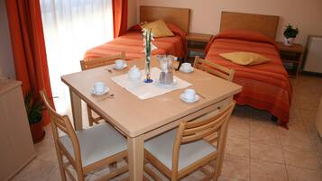 Une chambre d’hôtel avec deux lits, une table à manger avec des chaises et un petit coin cuisine.