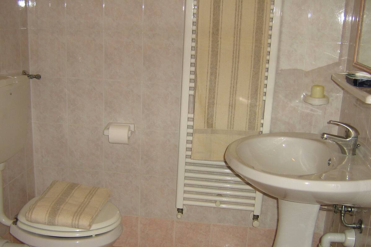 A bathroom with a toilet, a sink, and a mirror.