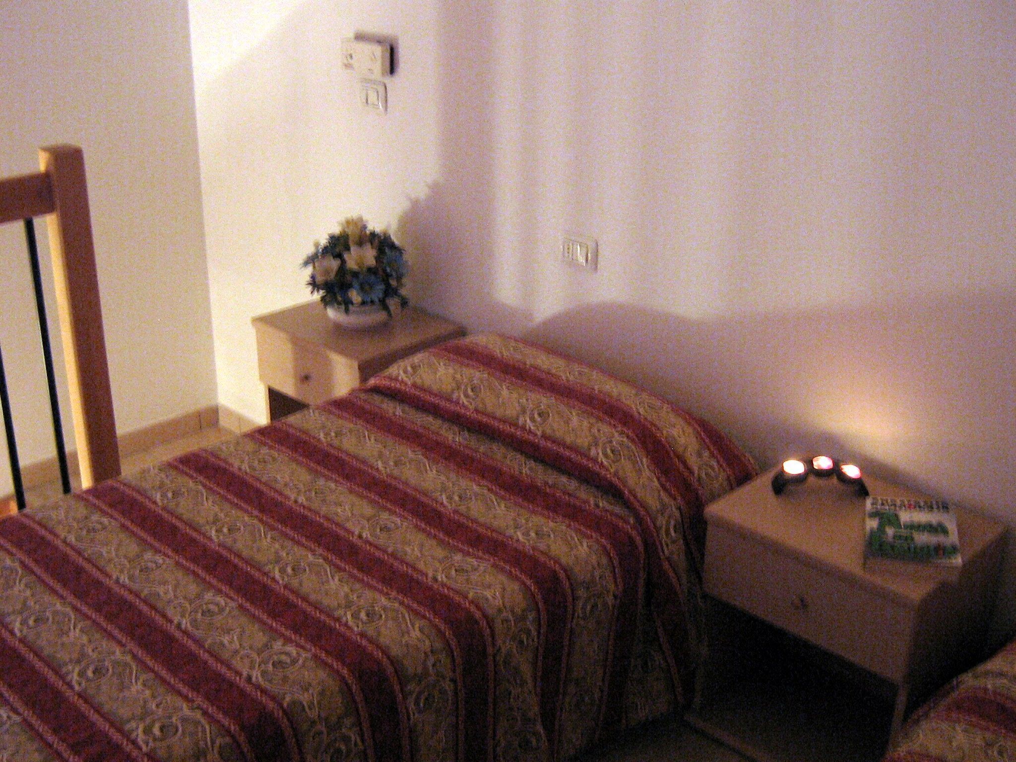 Ein Schlafzimmer mit einem Bett, einem Nachttisch, einer Lampe und einem kleinen Tisch mit einem Buch.