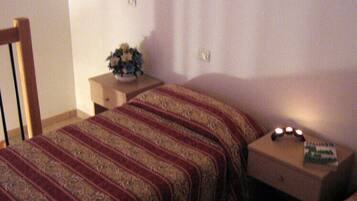 Ein Schlafzimmer mit einem Bett, einem Nachttisch, einer Lampe und einem kleinen Tisch mit einem Buch.