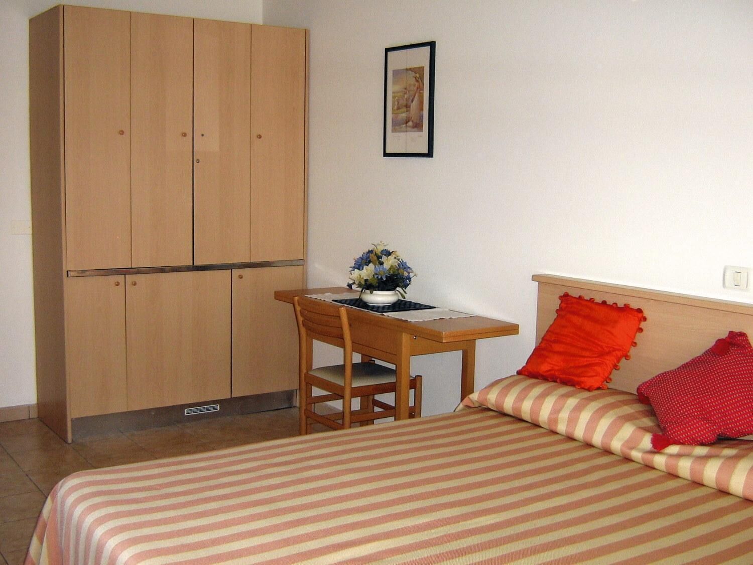 Ein Schlafzimmer mit Bett, Schreibtisch und Kleiderschrank.