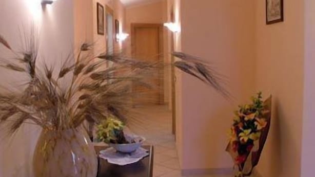 A hallway with a large potted plant, a small table with a bowl, and a framed picture on the wall. - Casalotto Inn (Aci Sant'Antonio)