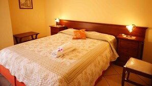 A neatly made bed with a rolled towel, two bedside tables with lamps, and a framed picture on the wall. - Casalotto Inn (Aci Sant'Antonio)