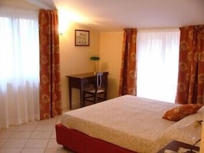 A hotel room with a bed, a desk, and a chair.