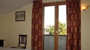 A bedroom with a bed, a chair, and a sliding glass door to a balcony. - Casalotto Inn (Aci Sant'Antonio)