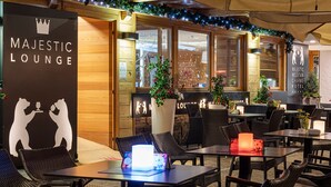 Un área de estar al aire libre en el Majestic Lounge, con mobiliario de mimbre y plantas en macetas.