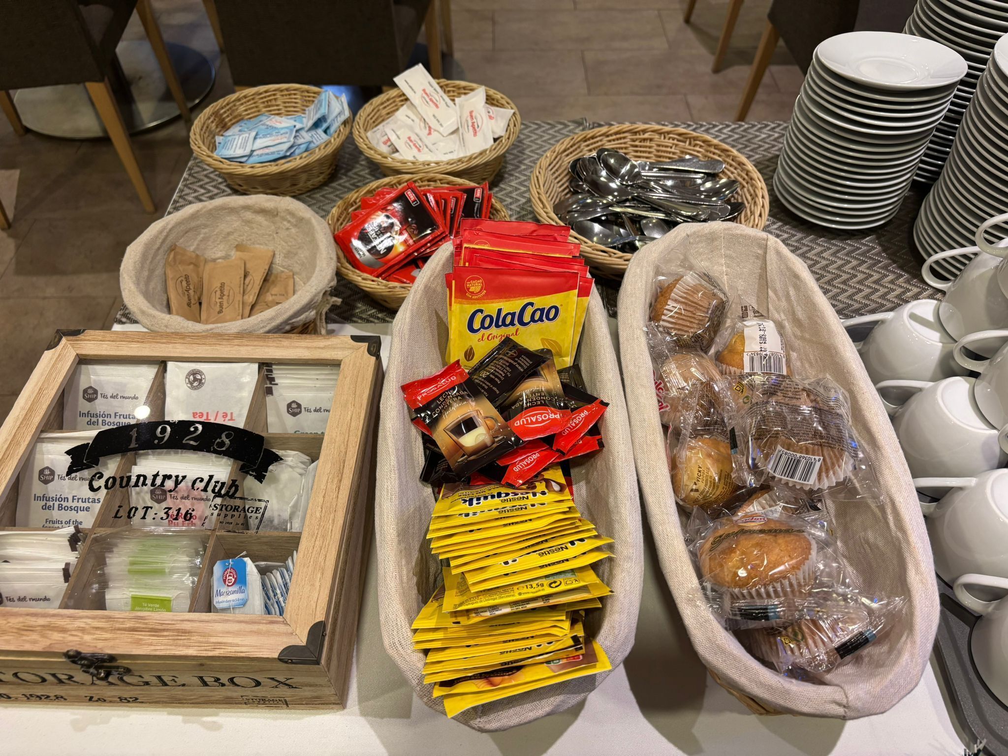 A table with various food items, including bread, snacks, and condiments.