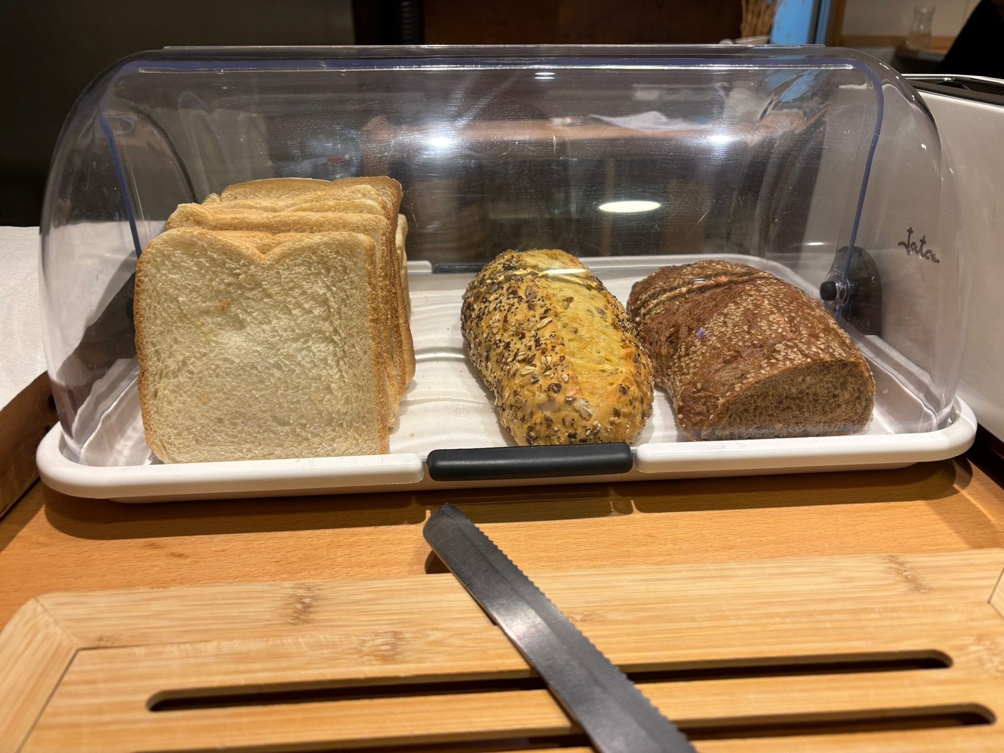 A bread display with three different types of bread under a clear plastic cover.