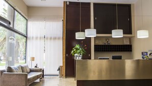 Een receptiezone met een bank, een receptiebalie en een potplant.