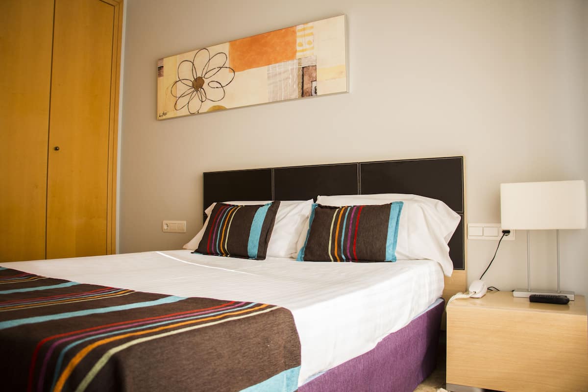 Une chambre d’hôtel avec un lit, une table de chevet, une lampe et une œuvre d’art murale.