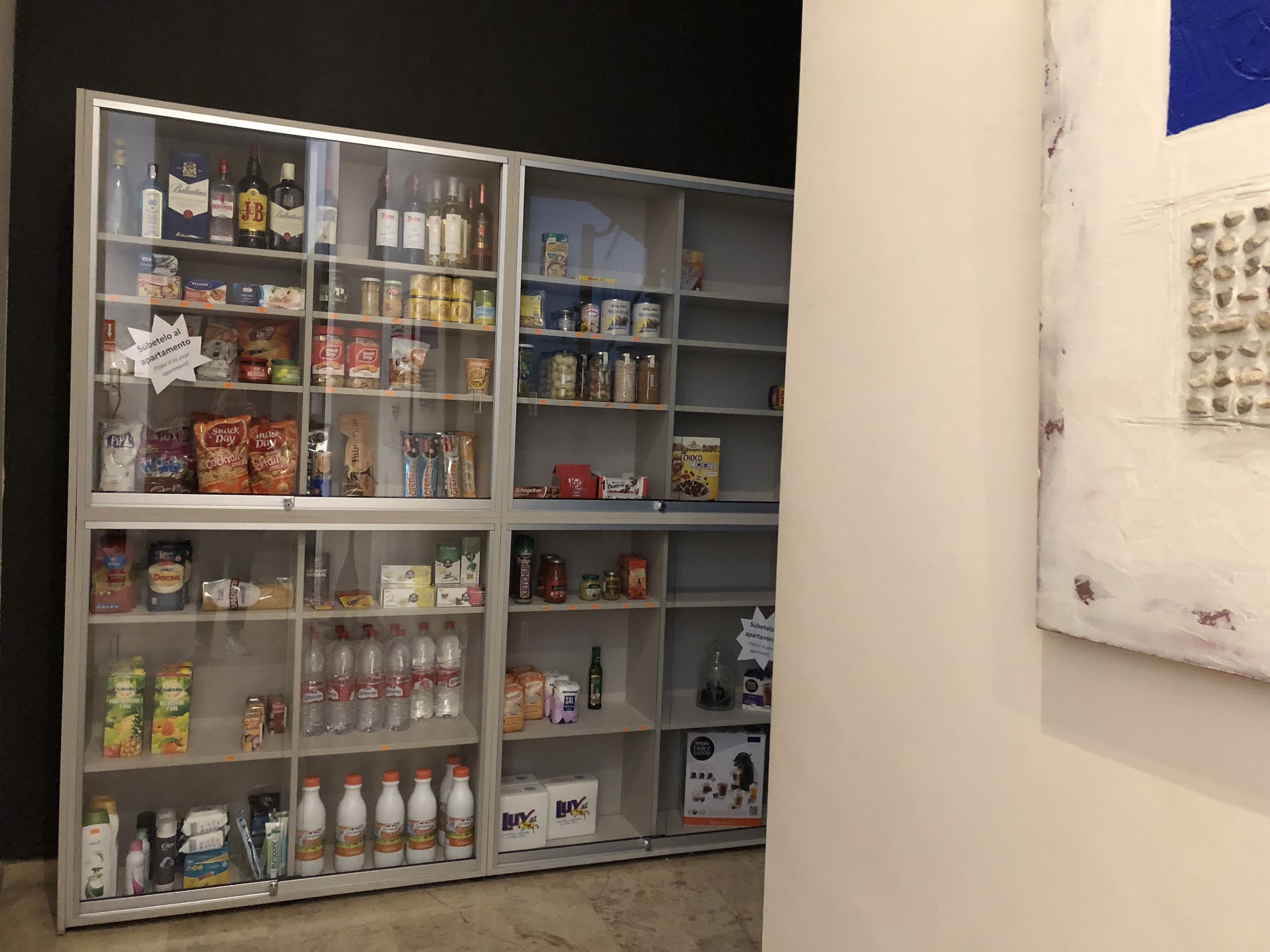 A multi-shelf display case with various food and drink items, including snacks, beverages, and condiments.