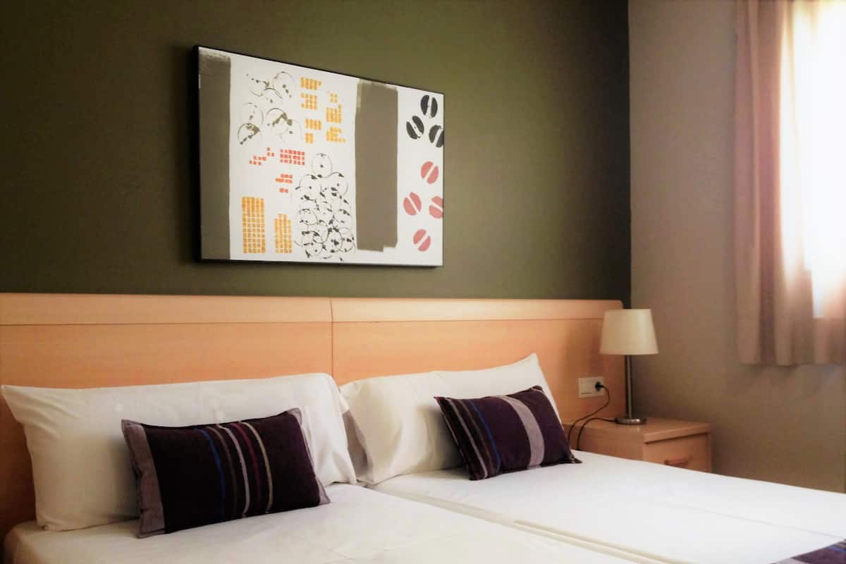 Une chambre d’hôtel avec un grand lit, deux oreillers, une table de chevet avec une lampe et une œuvre d’art murale.