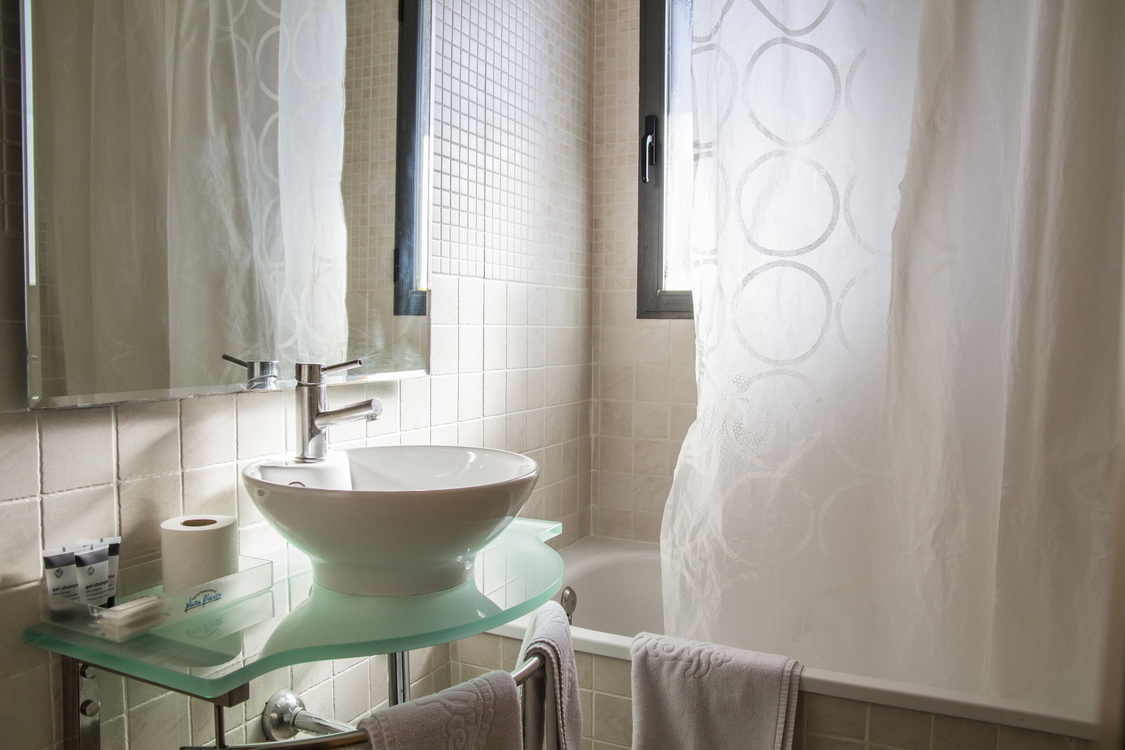 Une salle de bain avec un lavabo en verre, une baignoire et un rideau de douche.