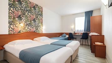 A hotel room with two beds, a desk, and a chair.