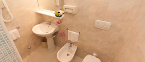 A modern bathroom with a sink, bidet, toilet, and a mirror.