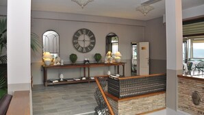 A reception area with a wooden console table, two wall clocks, and a staircase leading to an upper level. - Hotel San Luca (Cortona)