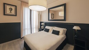 A hotel room with a large bed, a bedside table with a lamp, a mirror, and a framed picture on the wall. - Hotel San Luca (Cortona)