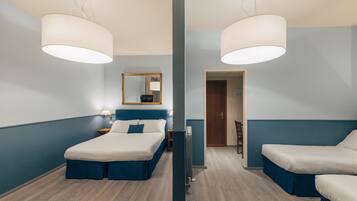 Habitación de hotel con dos camas, un espejo grande, un radiador y suelo de madera.
