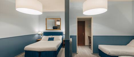 A hotel room with two beds, a large mirror, a radiator, and a wooden floor.