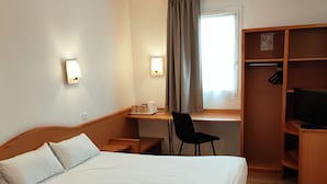 Une chambre d’hôtel avec deux lits, un bureau avec une chaise, une télévision et une armoire.