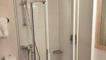Un baño con ducha de vidrio, un lavamanos blanco y un secador de manos.