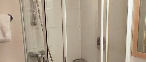 A bathroom with a glass-enclosed shower, a white sink, and a hand dryer.