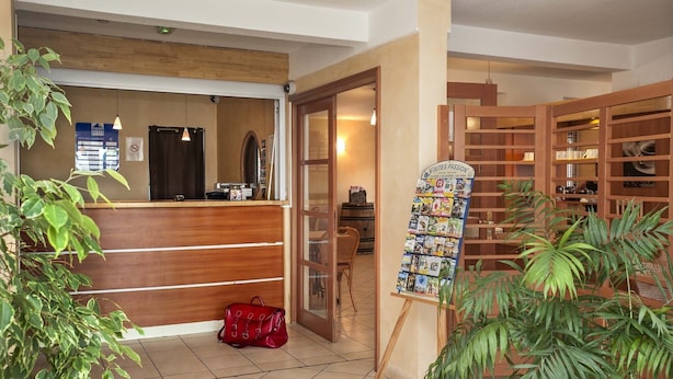 Un espace d’accueil avec un bureau en bois, un sac à main rouge et un panneau d’affichage où sont exposées des cartes postales.