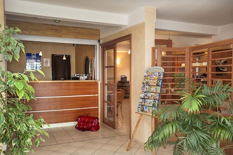 A reception area with a wooden desk, a red handbag, and a display board with postcards.