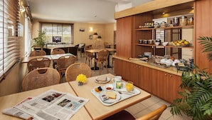 Un coin repas avec des meubles en bois, un comptoir de cuisine avec des aliments et un journal sur la table.
