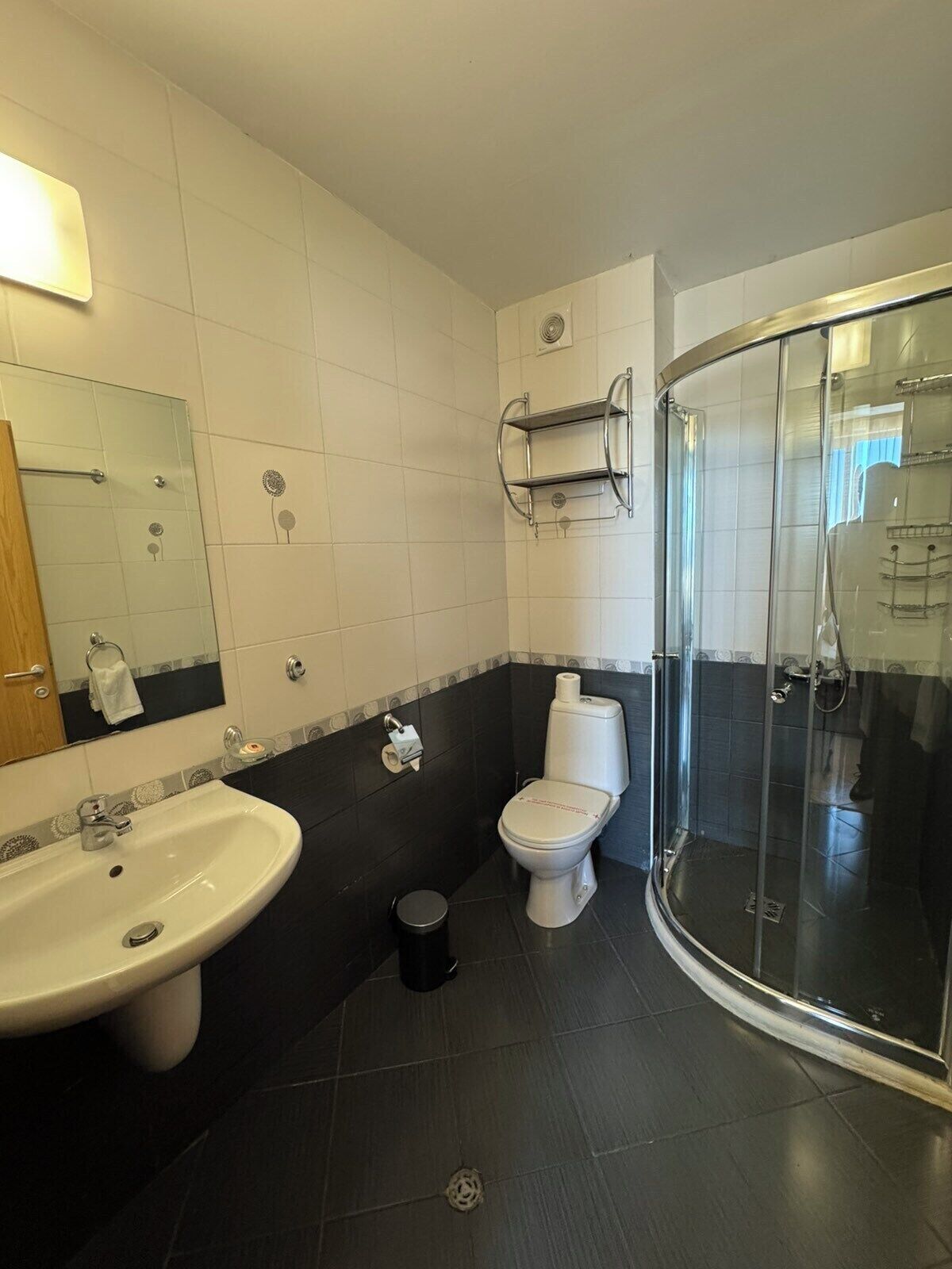 A bathroom with a sink, toilet, and glass shower enclosure.