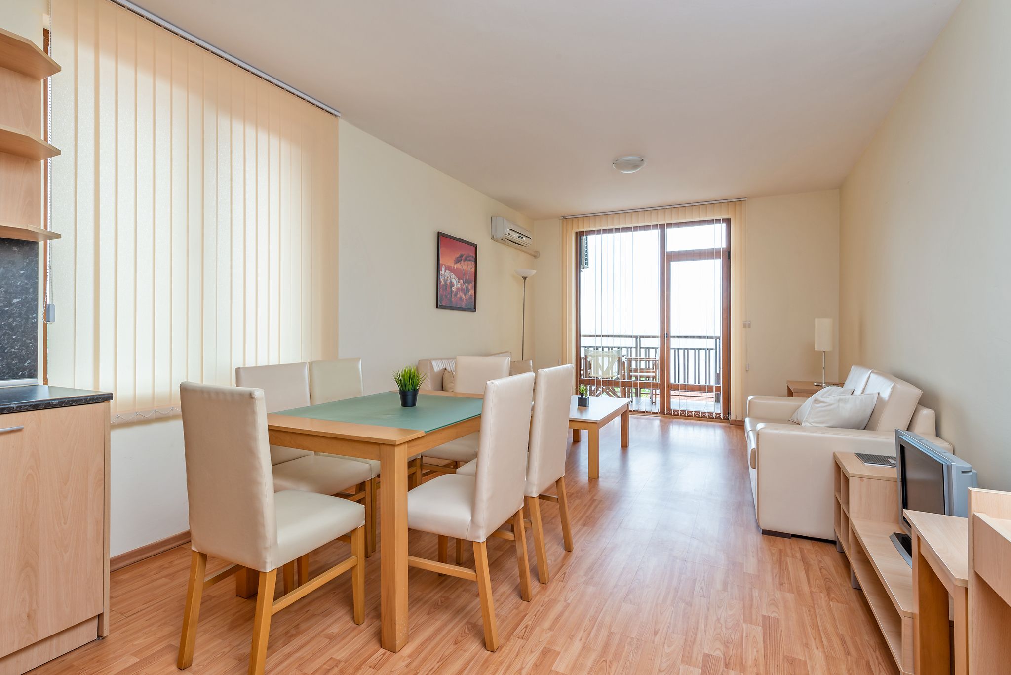 Una sala de estar moderna con una mesa de comedor de madera, sillas, un sofá y un televisor.