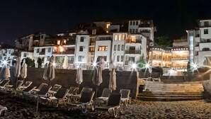 Un hotel fronte spiaggia con diversi balconi, lettini e ombrelloni.