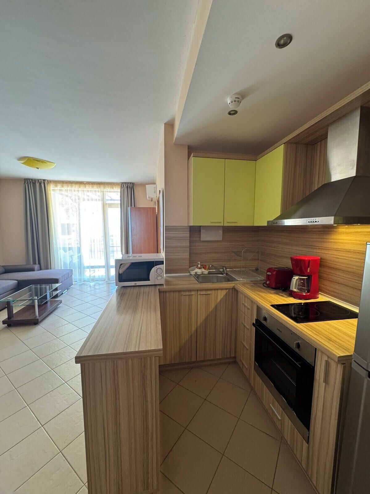 A compact kitchen with a microwave, sink, and red coffee maker.