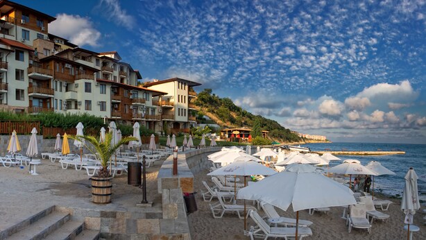 Un hotel sulla spiaggia con numerosi balconi, sdraio e ombrelloni.