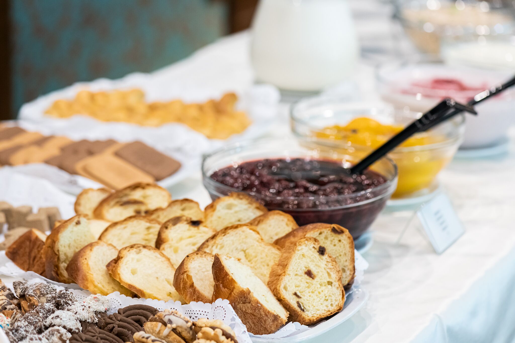 A buffet table with various food items including bread, pastries, and jams.