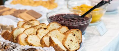 A buffet table with various food items including bread, pastries, and jams.