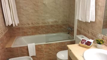 A bathroom with a bathtub, bidet, toilet, and sink.