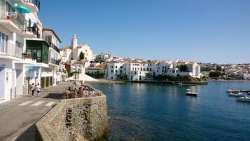 A coastal town with white buildings, a stone wall, and a clear blue sky.