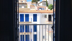 An open door leading to a balcony with a view of buildings and a tree. - Hotel Octavia (Cadaqués)