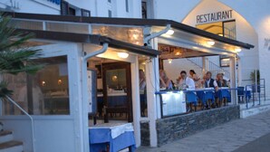 An outdoor restaurant with a stone facade, blue tables, and a sign indicating it is a restaurant. - Hotel Octavia (Cadaqués)