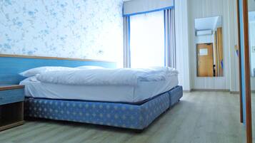A hotel room with a bed, a nightstand, a dresser, a mirror, and a window with curtains.