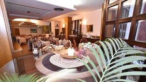 A dining area with round tables, chairs, and a central table with a candle and flowers. - Le Mura (Città di Castello)