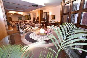 Un comedor con mesas redondas, sillas y una mesa central con una vela y flores.