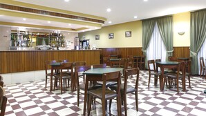 A restaurant with a checkered floor, wooden tables and chairs, a bar area with various bottles, and green curtains. - Domus Pacis Fatima Hotel (Ourem)