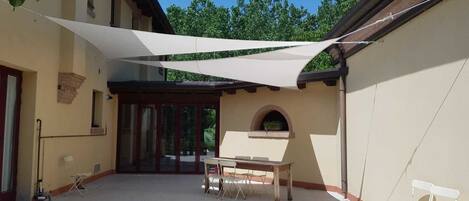 Un patio cubierto con una mesa y sillas, una ventana y un pequeño arco.