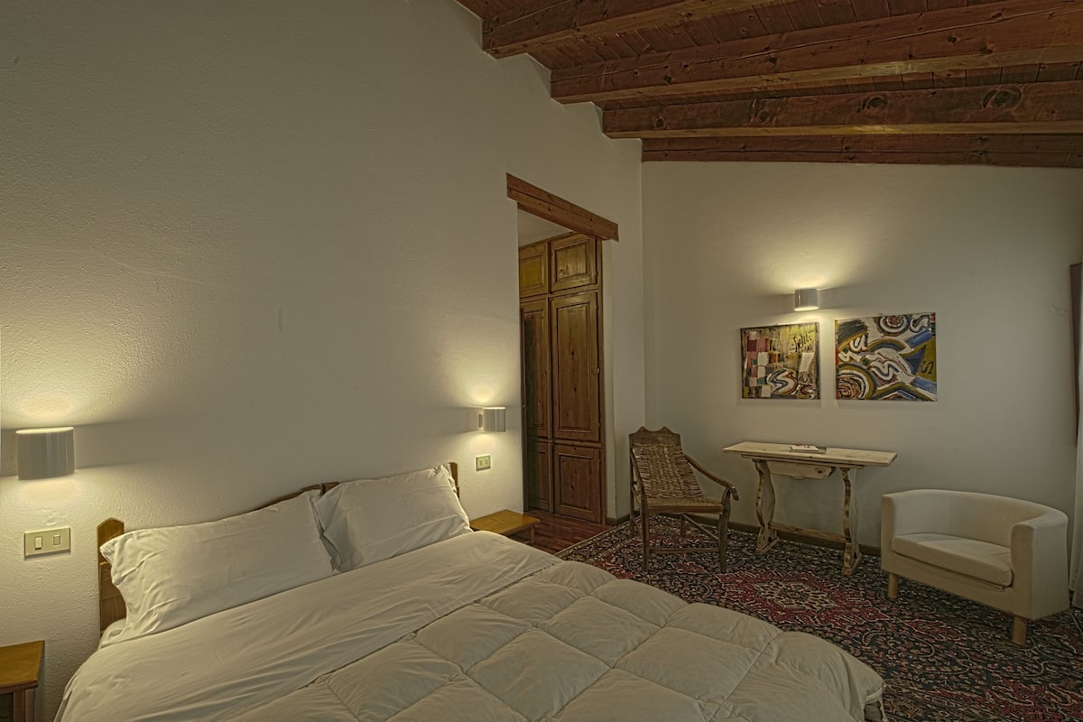 A bedroom with a bed, a desk, a chair, and a wardrobe.