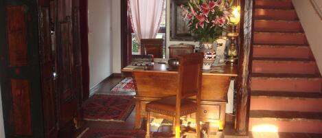 Un escritorio de madera con una silla, un jarrón con flores y una alfombra en el suelo.