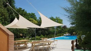 A poolside area with picnic tables and a pool. - Villa Belfiore (Ostellato)