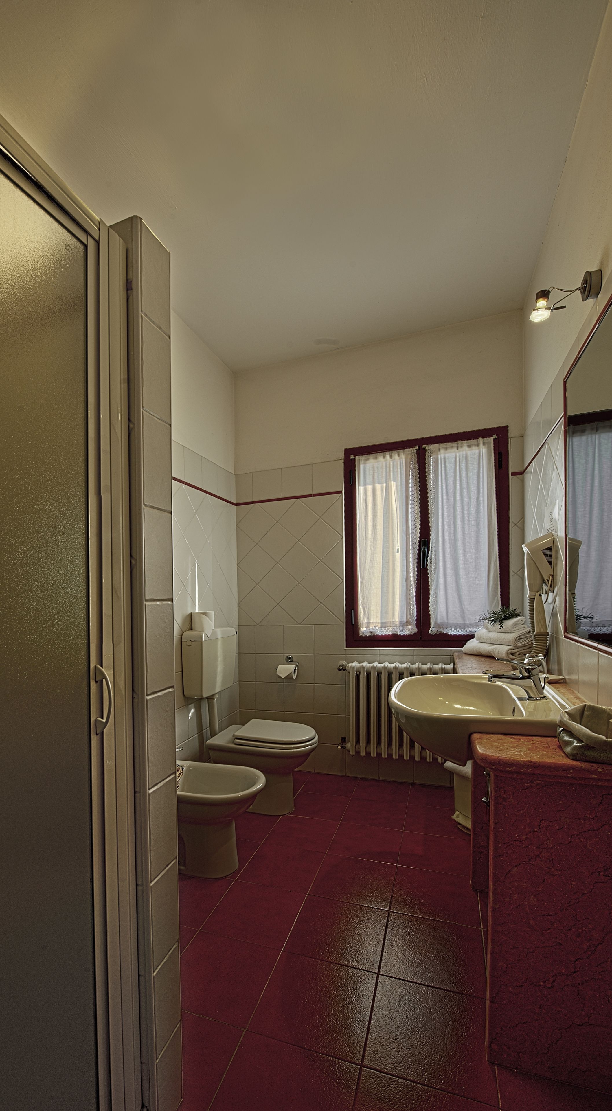 Une salle de bain équipée de toilettes, d’un bidet, d’un lavabo et d’un miroir.